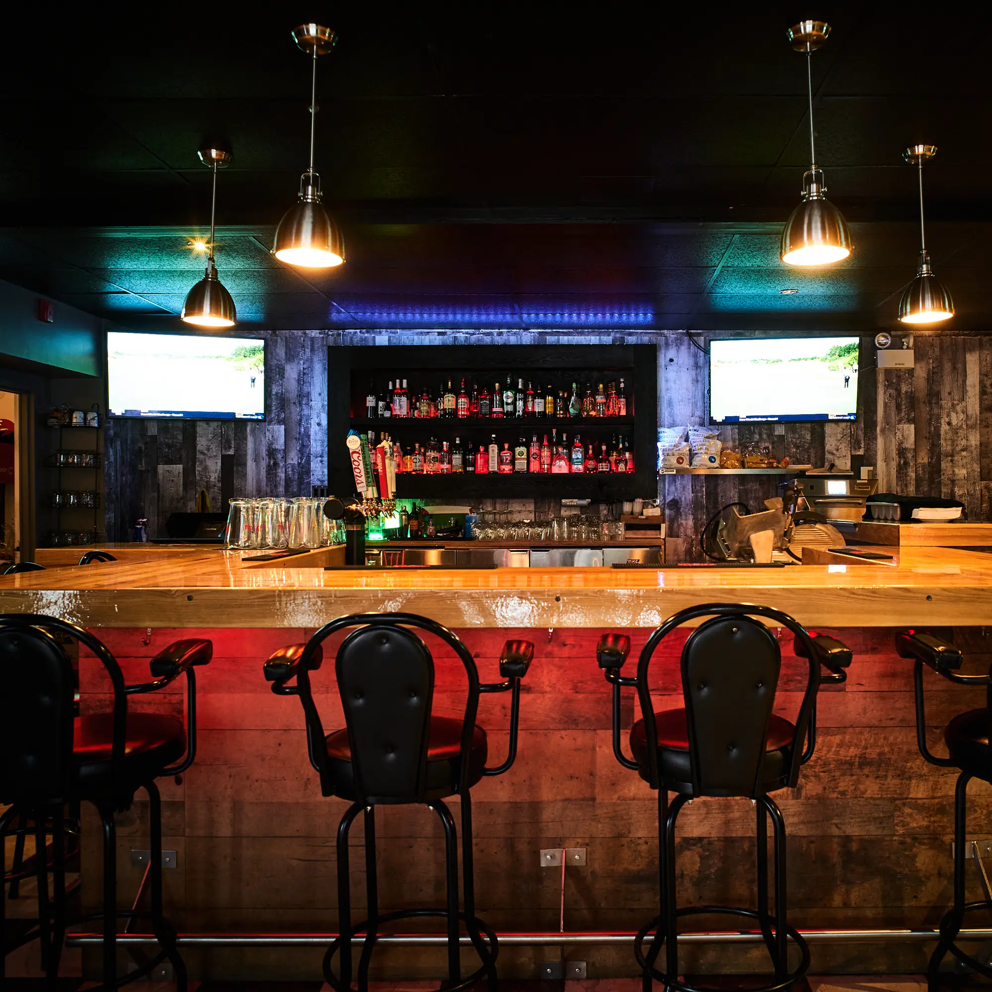 Bar central de la Taverne Gordon avec comptoir de bois et bouteilles de spiritueux bien en vue