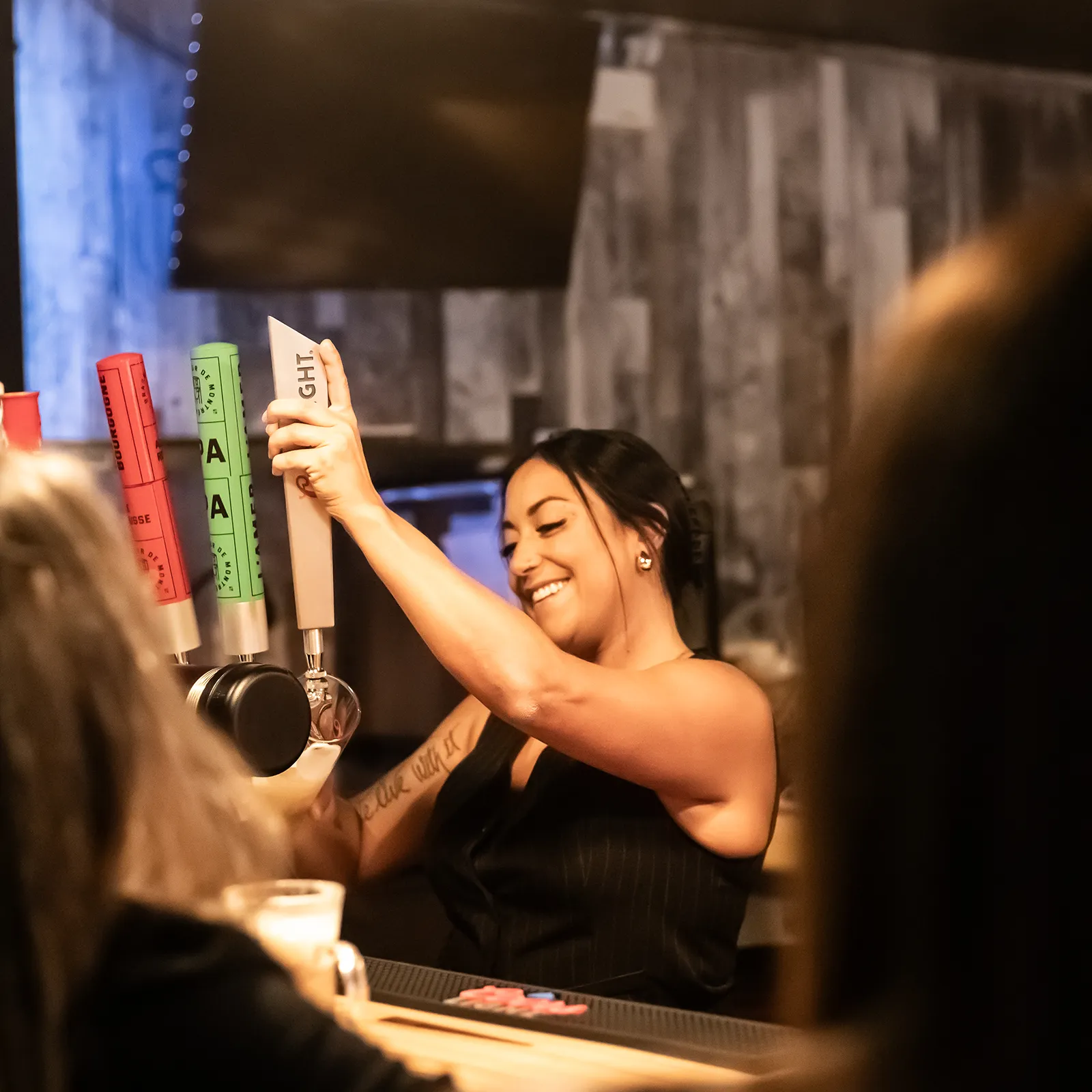 Serveuse souriante en train de couler une bière en fût à la Taverne Gordon