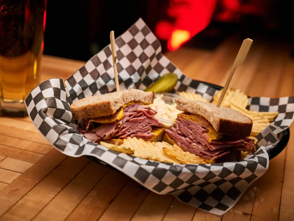 Smoked meat généreux servi avec chips maison et cornichons, dans l’ambiance chaleureuse de la Taverne Gordon