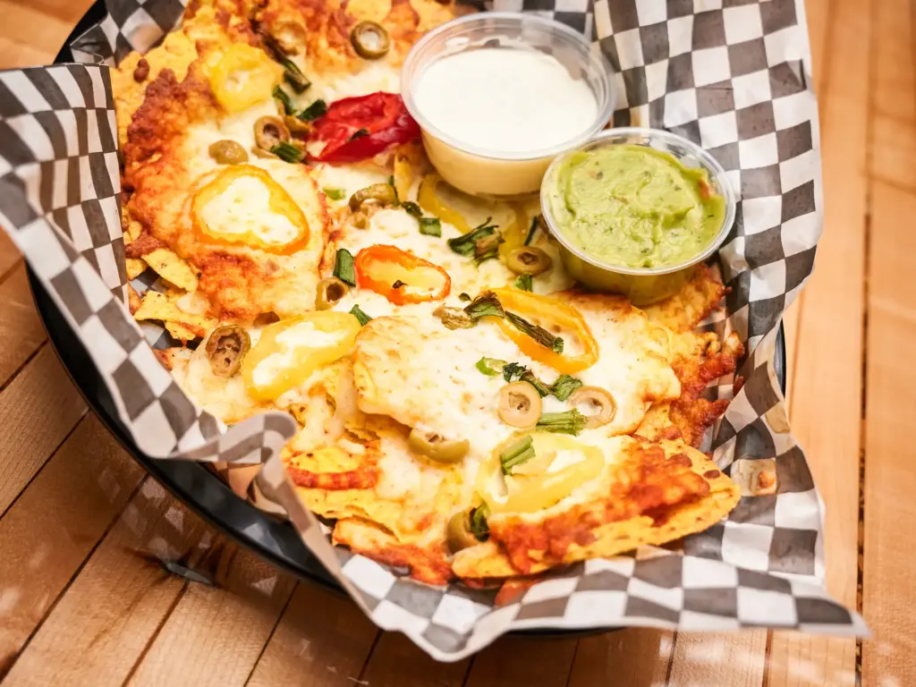 Nachos classiques garnis de salsa, crème sure, oignons verts, olives et piments forts – parfaits à partager à la Taverne Gordon