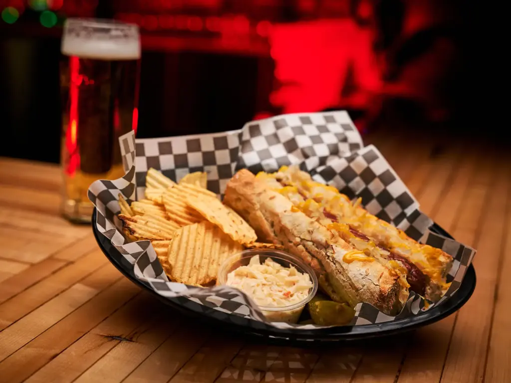 Hot-dog à l’européenne servi avec chips BBQ, salade de chou crémeuse et pickles à la Taverne Gordon